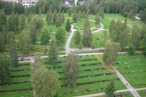Gravgården fotad uppifrån, gravar i rader och urnelunden syns. Sommargrönska