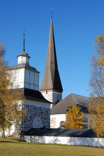Pedersöre kyrka och klockstapel omgiven av höstgula björkar